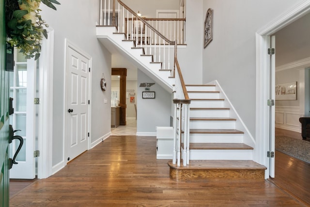 stairway with hardwood / wood-style flooring, a towering ceiling, and crown molding