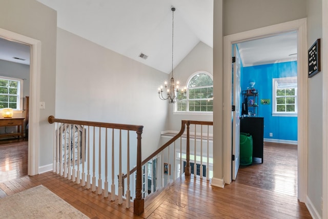 hallway with a chandelier, vaulted ceiling, and hardwood / wood-style flooring