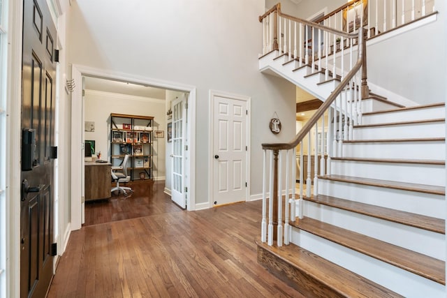 foyer with crown molding, dark hardwood / wood-style flooring, and a towering ceiling