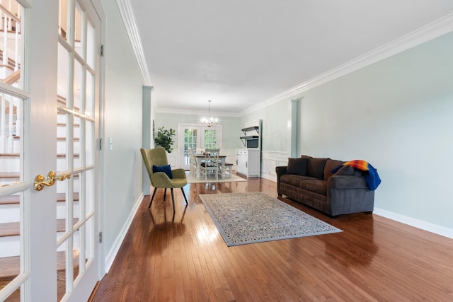 living room featuring a notable chandelier, wood-type flooring, crown molding, and french doors