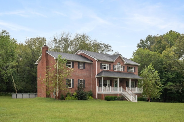 colonial inspired home featuring covered porch and a front yard