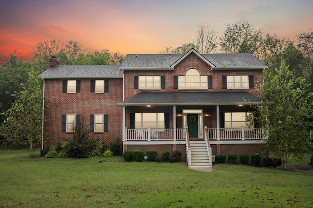 view of front facade with a lawn and covered porch