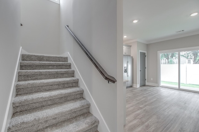 stairway with hardwood / wood-style floors and crown molding