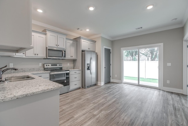 kitchen featuring light stone countertops, sink, light wood-type flooring, and stainless steel appliances