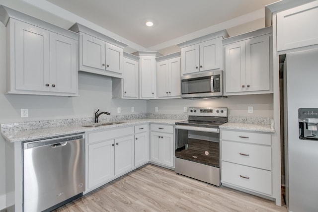 kitchen with sink, white cabinets, light hardwood / wood-style floors, and appliances with stainless steel finishes