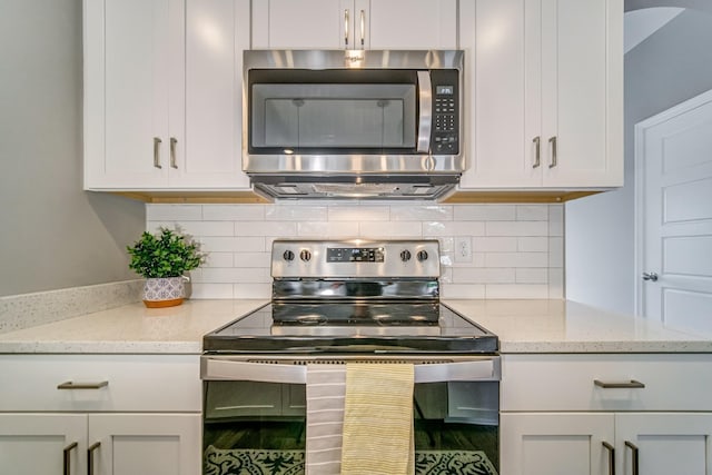 kitchen featuring white cabinets, backsplash, light stone countertops, and stainless steel appliances