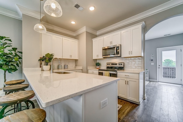 kitchen featuring sink, hanging light fixtures, kitchen peninsula, white cabinets, and appliances with stainless steel finishes