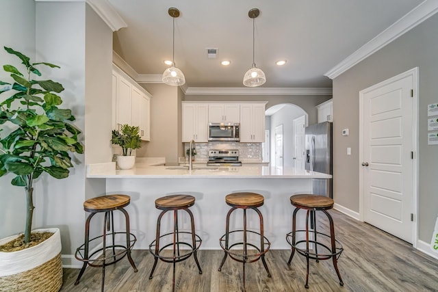 kitchen with backsplash, stainless steel appliances, decorative light fixtures, light hardwood / wood-style floors, and white cabinetry