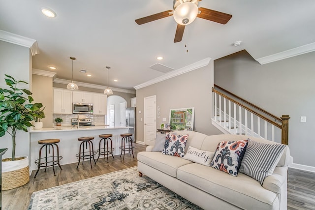 living room featuring ornamental molding, ceiling fan, and dark wood-type flooring