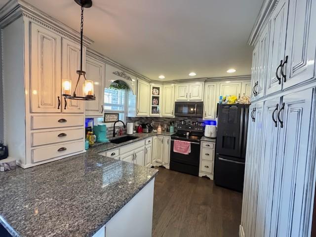 kitchen featuring kitchen peninsula, dark wood-type flooring, sink, black appliances, and hanging light fixtures