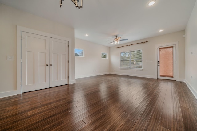 unfurnished living room with dark wood-type flooring and ceiling fan with notable chandelier