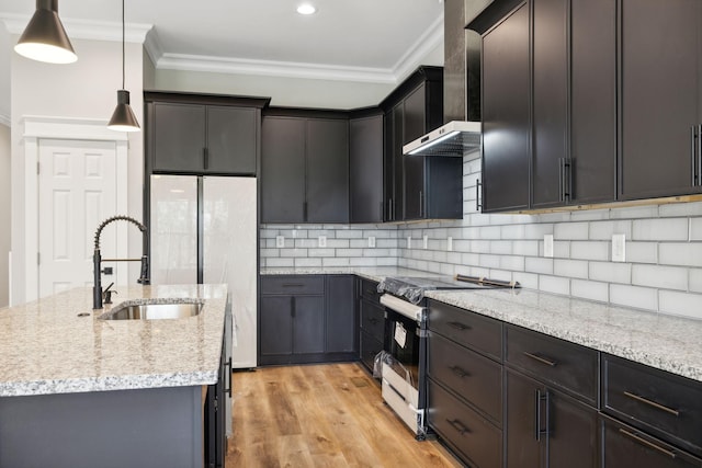 kitchen with sink, wall chimney range hood, range with electric stovetop, pendant lighting, and light hardwood / wood-style floors