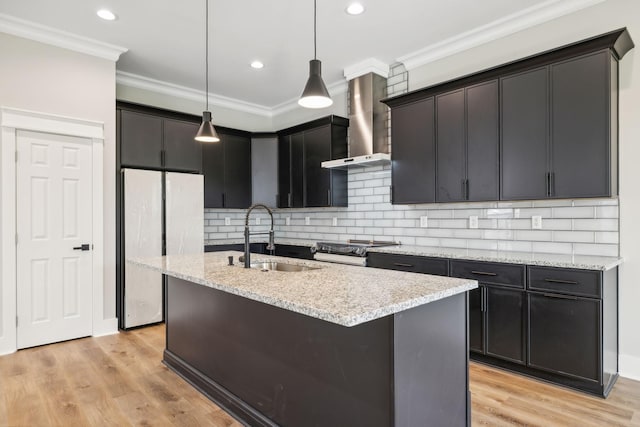 kitchen featuring sink, wall chimney range hood, light hardwood / wood-style flooring, stainless steel fridge, and pendant lighting