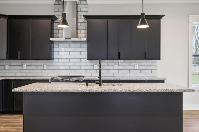 kitchen with hanging light fixtures, light hardwood / wood-style flooring, plenty of natural light, and wall chimney range hood