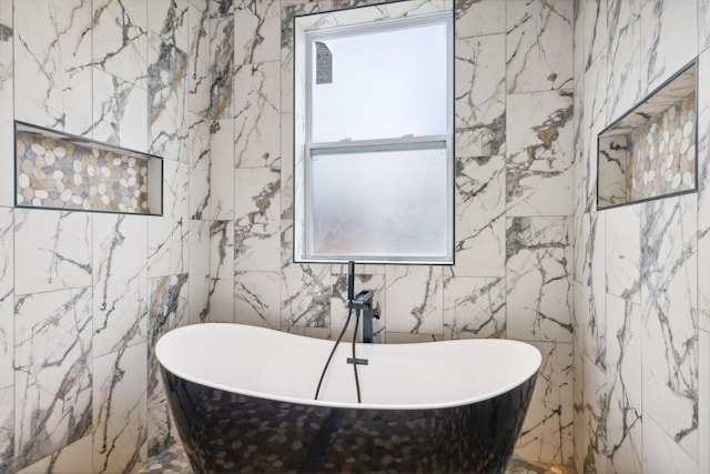 bathroom featuring a washtub and tile walls