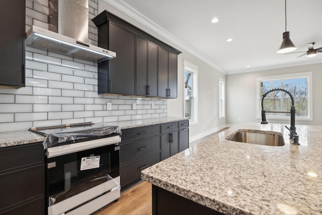 kitchen featuring range with gas cooktop, crown molding, sink, wall chimney range hood, and hanging light fixtures