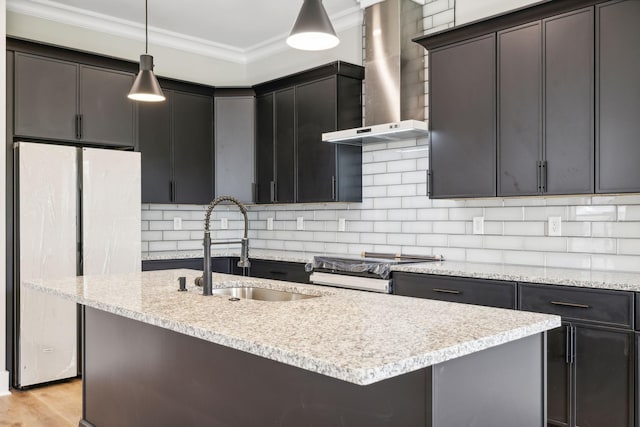 kitchen with sink, wall chimney exhaust hood, crown molding, decorative light fixtures, and fridge