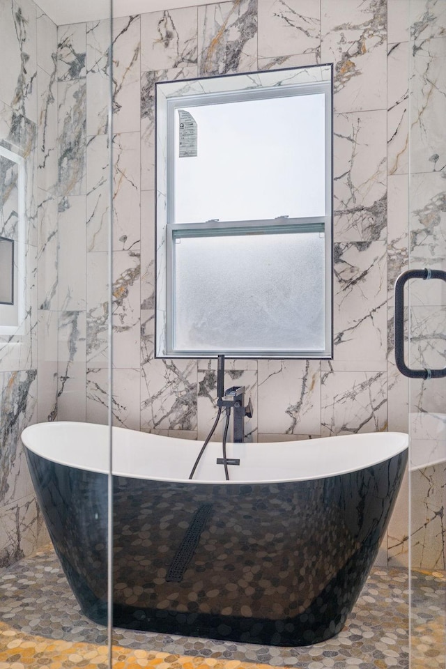 bathroom with a washtub and tile walls