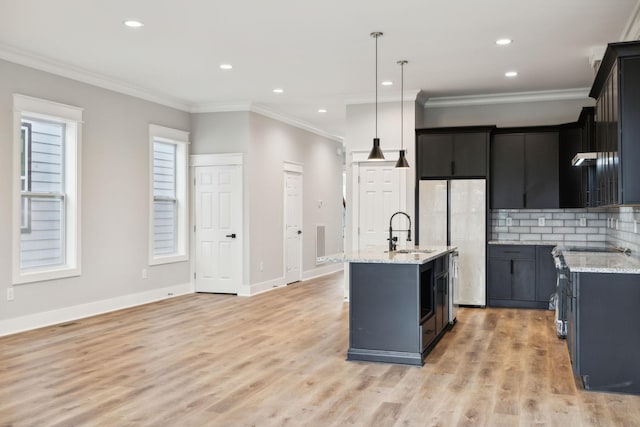 kitchen with decorative backsplash, ornamental molding, sink, pendant lighting, and a center island with sink