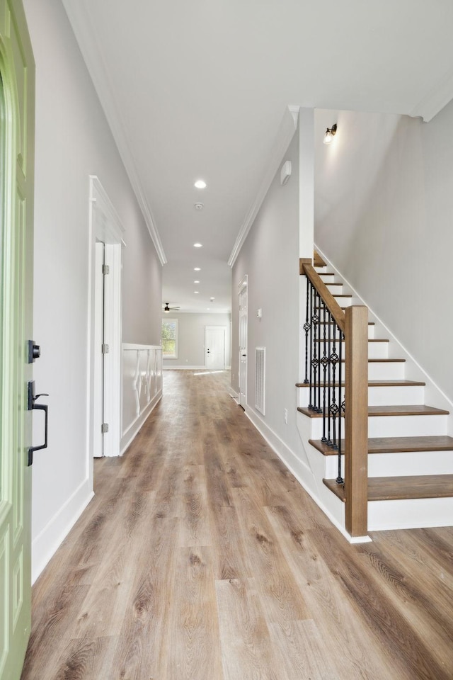 hall with ornamental molding and light hardwood / wood-style flooring