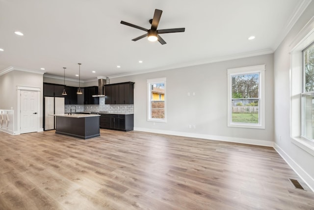 kitchen featuring stainless steel fridge, pendant lighting, a center island with sink, and a healthy amount of sunlight