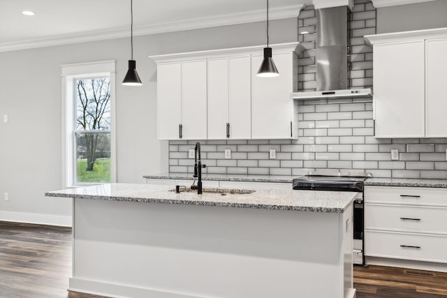 kitchen featuring white cabinets, an island with sink, and wall chimney range hood