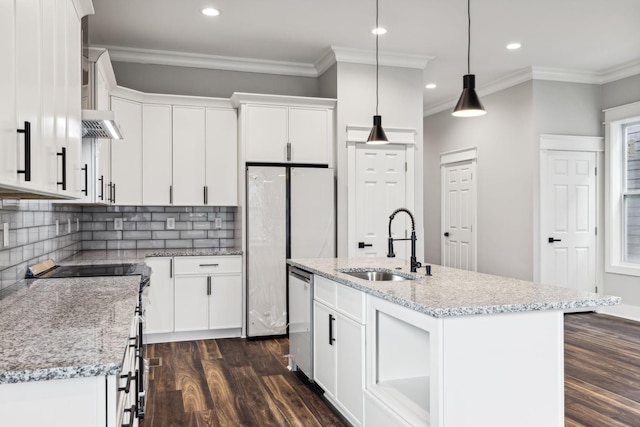 kitchen with decorative backsplash, a kitchen island with sink, sink, white cabinetry, and hanging light fixtures