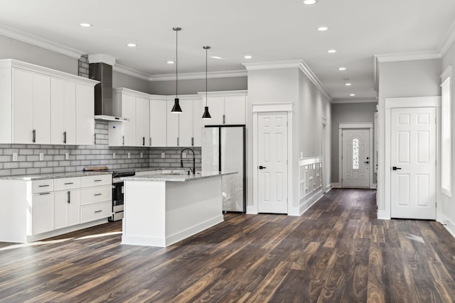 kitchen featuring white cabinetry, dark wood-type flooring, wall chimney range hood, an island with sink, and appliances with stainless steel finishes