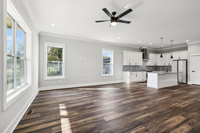 unfurnished living room featuring dark hardwood / wood-style floors, a healthy amount of sunlight, and ornamental molding