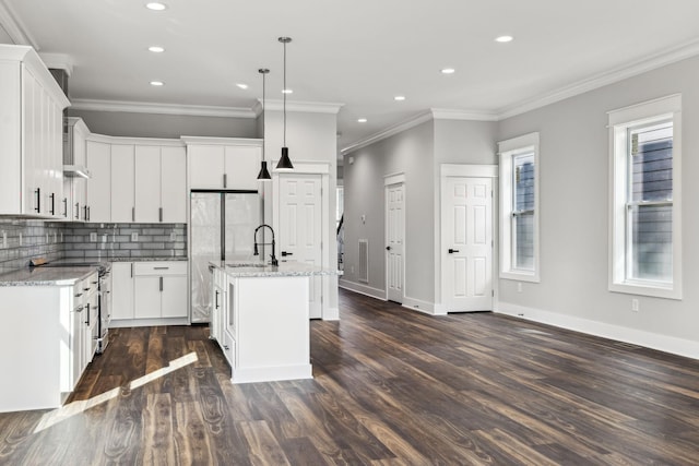 kitchen featuring a center island with sink, light stone counters, hanging light fixtures, and dark hardwood / wood-style floors