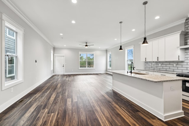 kitchen with white cabinetry, sink, ceiling fan, decorative light fixtures, and a center island with sink