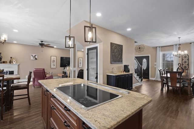 kitchen featuring a center island, dark hardwood / wood-style flooring, pendant lighting, black electric cooktop, and ceiling fan with notable chandelier