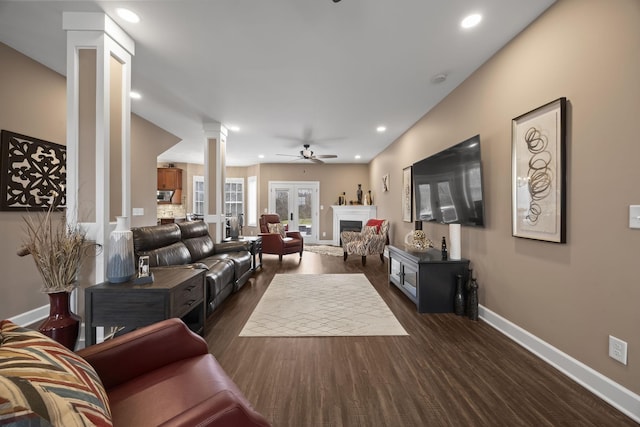 living room featuring dark hardwood / wood-style flooring, decorative columns, and ceiling fan