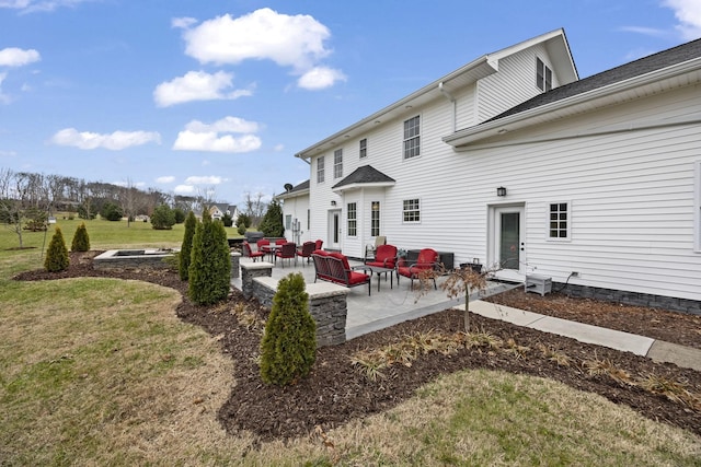 back of property featuring a patio area, a yard, and an outdoor hangout area