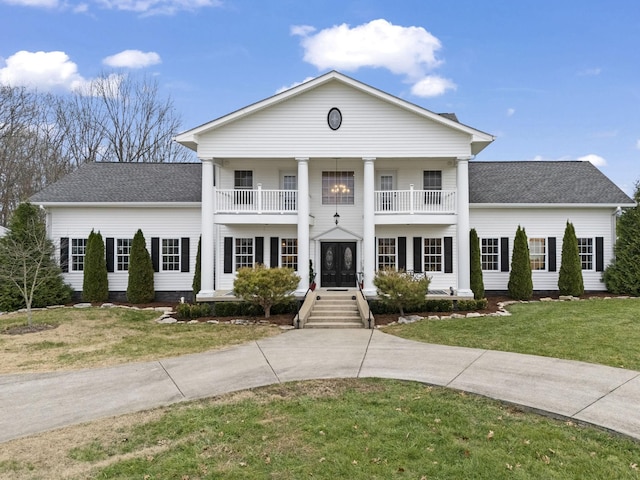 greek revival house featuring french doors, a balcony, and a front yard