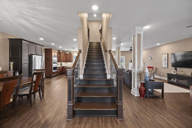 stairs featuring decorative columns, ceiling fan, and wood-type flooring