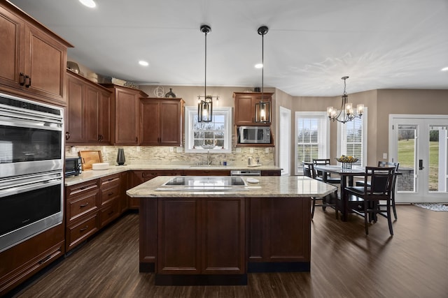 kitchen featuring a center island, stainless steel microwave, an inviting chandelier, hanging light fixtures, and black electric cooktop