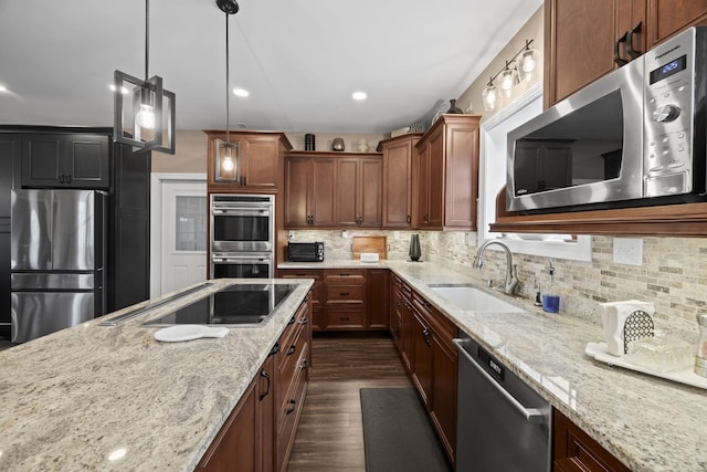 kitchen with backsplash, sink, hanging light fixtures, light stone countertops, and appliances with stainless steel finishes