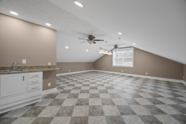 additional living space featuring a textured ceiling, ceiling fan, sink, and lofted ceiling