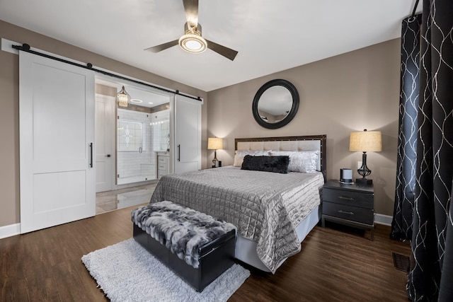 bedroom with ceiling fan, a barn door, and dark hardwood / wood-style flooring