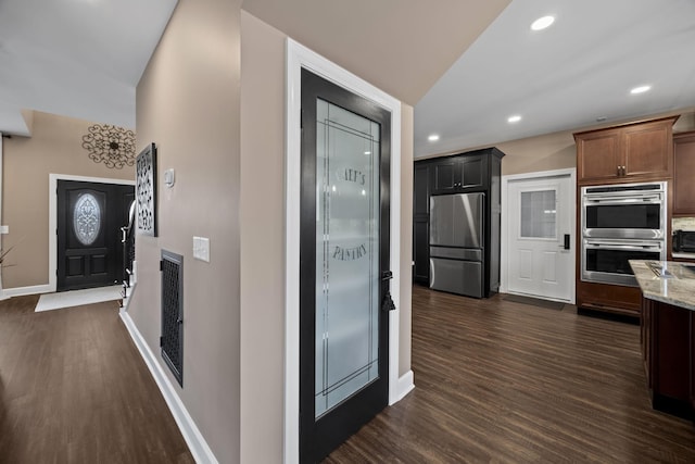 kitchen with dark hardwood / wood-style flooring, light stone countertops, and appliances with stainless steel finishes