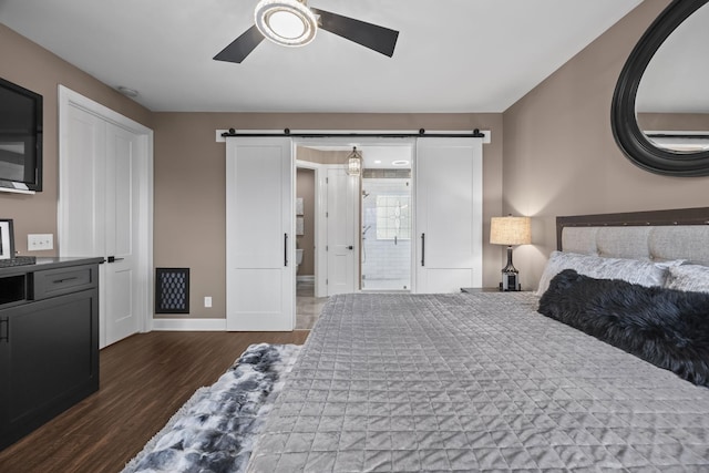 bedroom with ceiling fan, a barn door, and dark hardwood / wood-style flooring