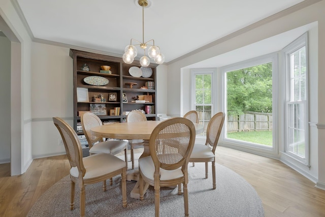 dining room featuring an inviting chandelier, light hardwood / wood-style flooring, and ornamental molding