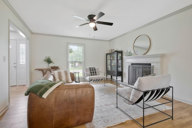 living room with a fireplace, crown molding, light hardwood / wood-style flooring, and ceiling fan