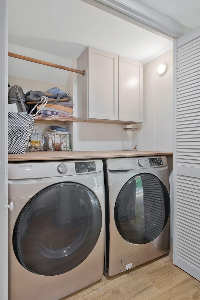 washroom featuring separate washer and dryer, light hardwood / wood-style flooring, and cabinets