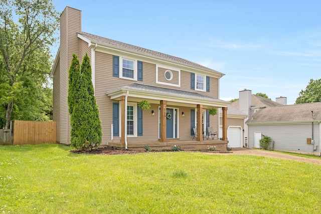 colonial inspired home featuring a front lawn, covered porch, an outdoor structure, and a garage