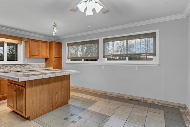 kitchen with tile counters, a kitchen island, light tile patterned floors, and tasteful backsplash