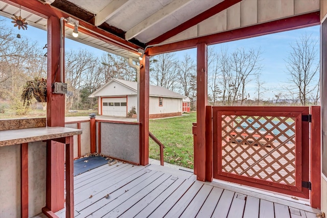 wooden terrace with a garage, an outdoor structure, and a lawn