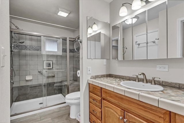 bathroom with hardwood / wood-style floors, vanity, an enclosed shower, and toilet