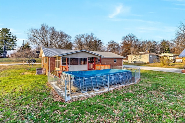 exterior space with central AC, a yard, and a covered pool